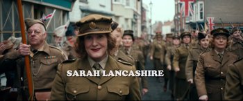 Movie still from “Dad's Army” (2016), directed by Oliver Parker – A group of people in uniforms marching down a street; Medium shot, High angle
