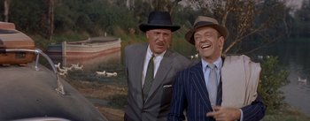 Movie still from “Daddy Long Legs” (1955), directed by Jean Negulesco – A couple of men standing next to each other in a field; Medium shot, Over the shoulder angle