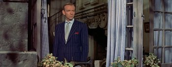 Movie still from “Daddy Long Legs” (1955), directed by Jean Negulesco – A man in a suit and tie standing in front of a window; Medium shot, Over the shoulder angle