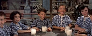 Movie still from “Daddy Long Legs” (1955), directed by Jean Negulesco – Two young children sitting at a table with milk; Medium shot, High angle