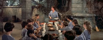 Movie still from “Daddy Long Legs” (1955), directed by Jean Negulesco – A group of people sitting around a table eating food; Medium shot, High angle