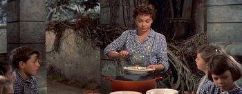 Movie still from “Daddy Long Legs” (1955), directed by Jean Negulesco – A woman in a checkered shirt stirring a pot of food; Medium shot, Low angle