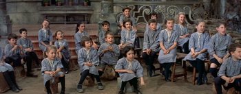 Movie still from “Daddy Long Legs” (1955), directed by Jean Negulesco – A group of children sitting on a bench in a room; Medium shot, High angle