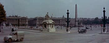 Movie still from “Daddy Long Legs” (1955), directed by Jean Negulesco – A statue of a man sitting on a pedestal in front of a building; Extreme Wide shot, High angle
