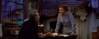 Movie still from “Daddy Long Legs” (1955), directed by Jean Negulesco – A woman standing next to a man at a table; Medium shot, Over the shoulder angle