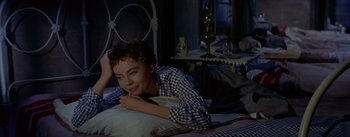Movie still from “Daddy Long Legs” (1955), directed by Jean Negulesco – A woman laying on a bed in a room; Medium shot, High angle
