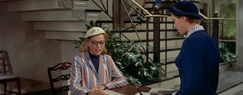 Movie still from “Daddy Long Legs” (1955), directed by Jean Negulesco – A woman sitting at a table writing on a piece of paper; Medium shot, High angle