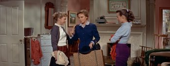 Movie still from “Daddy Long Legs” (1955), directed by Jean Negulesco – A group of people standing around a living room; Medium shot, Over the shoulder angle