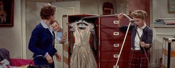 Movie still from “Daddy Long Legs” (1955), directed by Jean Negulesco – Three people are looking at a dress in a closet; Medium shot, Over the shoulder angle