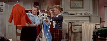 Movie still from “Daddy Long Legs” (1955), directed by Jean Negulesco – Two young women looking at dresses on a clothes rack; Medium shot, Low angle
