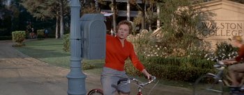 Movie still from “Daddy Long Legs” (1955), directed by Jean Negulesco – A woman riding a bike next to a mail box; Medium shot, Low angle