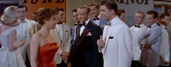 Movie still from “Daddy Long Legs” (1955), directed by Jean Negulesco – A group of men and women standing next to each other in tuxedos; Medium shot, Over the shoulder angle