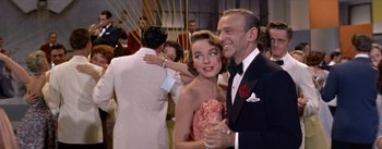 Movie still from “Daddy Long Legs” (1955), directed by Jean Negulesco – A man and a woman dancing in front of other people; Medium shot, Low angle