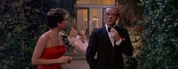 Movie still from “Daddy Long Legs” (1955), directed by Jean Negulesco – A man in a tuxedo and a woman in a red dress; Medium shot, Over the shoulder angle