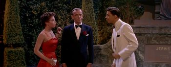 Movie still from “Daddy Long Legs” (1955), directed by Jean Negulesco – A man in a tuxedo standing next to two other men; Medium shot, Over the shoulder angle