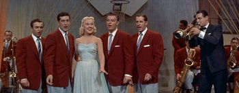 Movie still from “Daddy Long Legs” (1955), directed by Jean Negulesco – A group of men and a woman singing together; Medium shot, Low angle