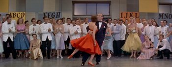 Movie still from “Daddy Long Legs” (1955), directed by Jean Negulesco – A man and a woman dancing in front of a crowd; Wide shot, Low angle