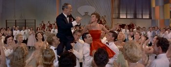 Movie still from “Daddy Long Legs” (1955), directed by Jean Negulesco – A group of people sitting around each other in a room; Wide shot, High angle