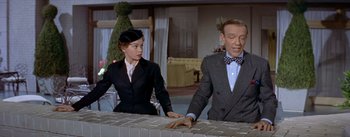 Movie still from “Daddy Long Legs” (1955), directed by Jean Negulesco – A man and a woman standing at a counter; Medium shot, Over the shoulder angle