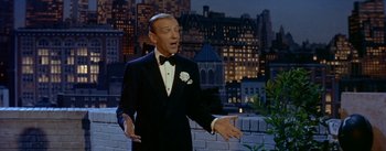 Movie still from “Daddy Long Legs” (1955), directed by Jean Negulesco – A man wearing a tuxedo and a bow tie standing in front of a building; Medium shot, High angle