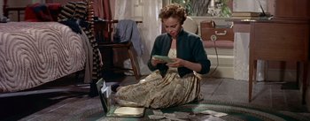 Movie still from “Daddy Long Legs” (1955), directed by Jean Negulesco – A woman sitting on the floor looking at a cell phone; Medium shot, High angle