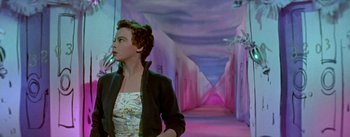 Movie still from “Daddy Long Legs” (1955), directed by Jean Negulesco – A woman standing in a hallway with pink lighting; Medium shot, Low angle