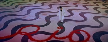 Movie still from “Daddy Long Legs” (1955), directed by Jean Negulesco – A man in a white robe standing in a room with red and black swirls on the floor; Extreme Wide shot, High angle