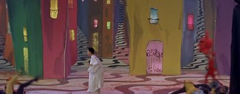 Movie still from “Daddy Long Legs” (1955), directed by Jean Negulesco – A man in a white robe walking in a room with colorful walls; Extreme Wide shot, High angle