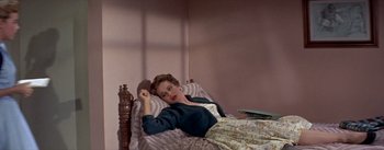 Movie still from “Daddy Long Legs” (1955), directed by Jean Negulesco – A woman laying in a bed with a teddy bear; Medium shot, High angle