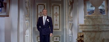 Movie still from “Daddy Long Legs” (1955), directed by Jean Negulesco – A man in a suit standing in front of a wall; Medium shot, Low angle
