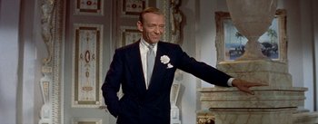 Movie still from “Daddy Long Legs” (1955), directed by Jean Negulesco – A man wearing a suit and tie in a room; Medium shot, Low angle