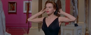 Movie still from “Daddy Long Legs” (1955), directed by Jean Negulesco – A woman in a black dress holding her hair; Medium shot, Low angle
