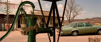 Movie still from “The Hills Have Eyes” (2006), directed by Alexandre Aja – A green fire hydrant in front of an old car; Wide shot, Over the shoulder angle