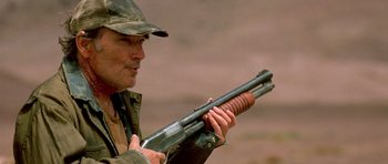 Movie still from “The Hills Have Eyes” (2006), directed by Alexandre Aja – A man holding a rifle in his hands; Close Up shot, Low angle