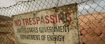 Movie still from “The Hills Have Eyes” (2006), directed by Alexandre Aja – A rusted sign on the side of a fence; Extreme Wide shot, Low angle