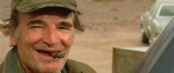 Movie still from “The Hills Have Eyes” (2006), directed by Alexandre Aja – An older man with a hat and a pipe in his mouth; Close Up shot, Low angle