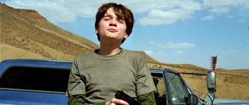 Movie still from “The Hills Have Eyes” (2006), directed by Alexandre Aja – A young man holding a gun while standing next to a car; Close Up shot, Low angle