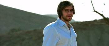 Movie still from “The Hills Have Eyes” (2006), directed by Alexandre Aja – A man in a white shirt is standing outside; Close Up shot, Over the shoulder angle