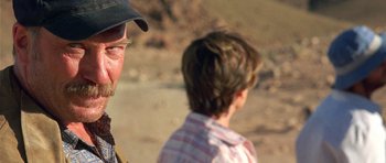 Movie still from “The Hills Have Eyes” (2006), directed by Alexandre Aja – A man standing next to a young boy on a beach; Close Up shot, Over the shoulder angle
