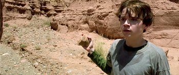 Movie still from “The Hills Have Eyes” (2006), directed by Alexandre Aja – A person holding a rock in a desert area; Close Up shot, High angle