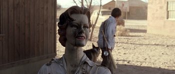 Movie still from “The Hills Have Eyes” (2006), directed by Alexandre Aja – A statue of a woman with a baseball bat in her mouth; Close Up shot, Over the shoulder angle
