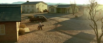 Movie still from “The Hills Have Eyes” (2006), directed by Alexandre Aja – A man walking a dog on a dirt road near a car; Extreme Wide shot, High angle