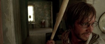 Movie still from “The Hills Have Eyes” (2006), directed by Alexandre Aja – A person holding a wooden baseball bat in a room; Close Up shot, Over the shoulder angle