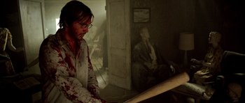 Movie still from “The Hills Have Eyes” (2006), directed by Alexandre Aja – A man in a room with blood all over his face; Medium shot, High angle