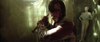 Movie still from “The Hills Have Eyes” (2006), directed by Alexandre Aja – A man holding a baseball bat in a room; Medium shot, Over the shoulder angle
