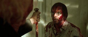 Movie still from “The Hills Have Eyes” (2006), directed by Alexandre Aja – A man holding a wooden stick with blood on it; Close Up shot, Over the shoulder angle