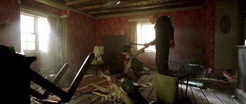 Movie still from “The Hills Have Eyes” (2006), directed by Alexandre Aja – A man holding an axe in a room with other people; Wide shot, High angle