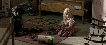 Movie still from “The Hills Have Eyes” (2006), directed by Alexandre Aja – A little girl sitting on the floor next to a box of toys; Medium shot, High angle