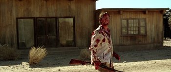 Movie still from “The Hills Have Eyes” (2006), directed by Alexandre Aja – A man with a bloody shirt on holding a rifle; Medium shot, Low angle