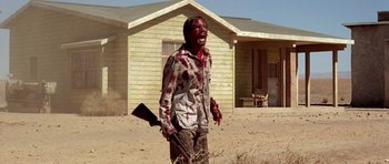 Movie still from “The Hills Have Eyes” (2006), directed by Alexandre Aja – A man with blood all over his face holding a gun; Medium shot, Low angle